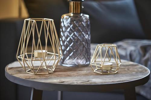 two gold candles on a table with a glass bottle at Chalet Wallehen in Saalbach Hinterglemm