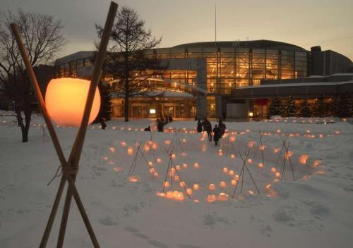 a building with a lot of lights in the snow at Business Inn Norte in Sapporo