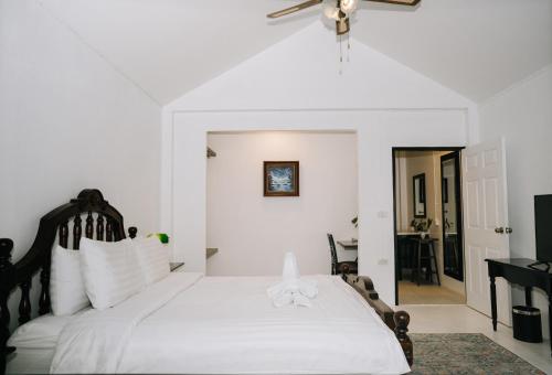 a bedroom with a white bed with a ceiling fan at The Courtyard Chiangrai in Chiang Rai