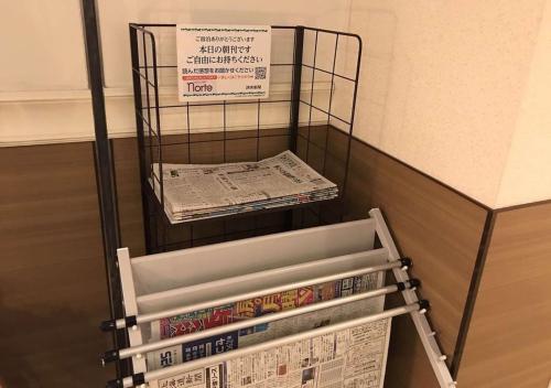 a stack of dvds and a newspaper on a shelf at Business Inn Norte in Sapporo