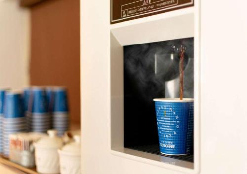 a microwave with a drink in a blue cup at Business Inn Norte in Sapporo