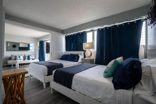 ホノルルにある2 bedroom Waikiki Condo Sleeps 6 Free Parkingのベッドルーム1室(ベッド2台、青いカーテン付)
