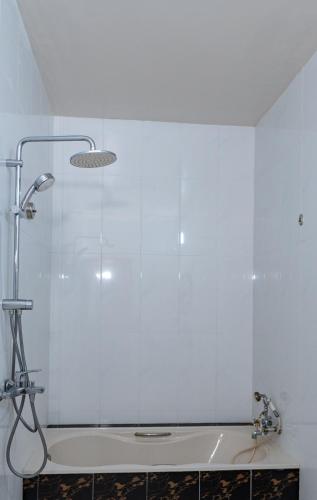 a shower in a white bathroom with a tub at Shark lounge in Fuvahmulah