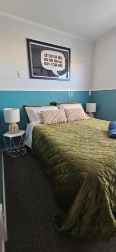 a bedroom with a large bed and a sign on the wall at Arty Apartments in Tauranga