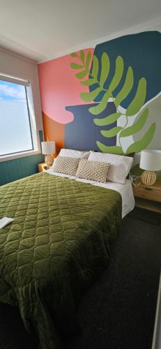 a bedroom with a green bed and a colorful wall at Arty Apartments in Tauranga
