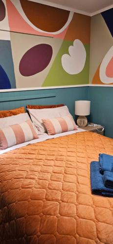 a bedroom with a large bed with a painting on the wall at Arty Apartments in Tauranga