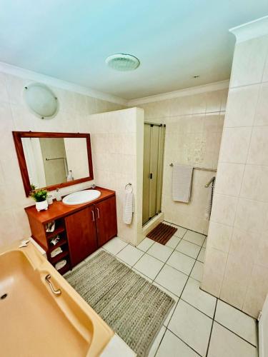 a bathroom with a sink and a shower and a mirror at Bonita Vista Plattekloof in Cape Town