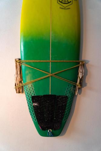 a surfboard is hanging on a wall at The Cafecito Surfhouse - Santa Teresa in Santa Teresa Beach