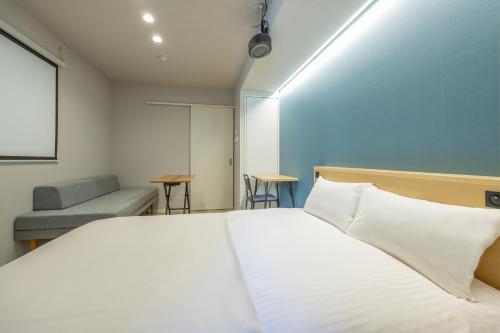 Un dormitorio con una gran cama blanca y un sofá. en Minn Umeda Nakazakicho, en Osaka