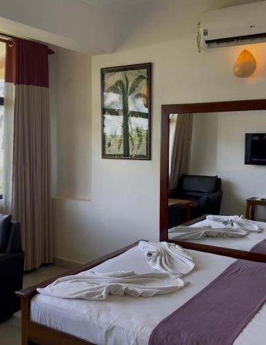 a hotel room with two beds and a mirror at Lavinia Blue Hotel in Mount Lavinia