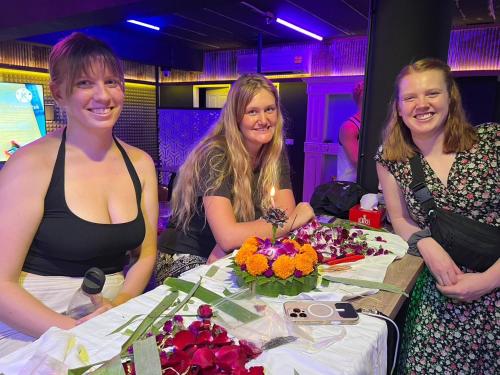 three women are sitting at a table with flowers at Here We Go Bangkok in Bangkok