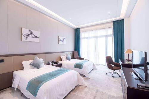 a hotel room with two beds and a television at Ramada Plaza Sino-Bay Shanghai in Fengxian