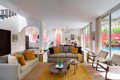 a living room with couches and a table at La Verona - 2,3,4 BHK Villas in Assagao with Private Pool, Garden, Caretaker, Kitchen & Security in Assagao