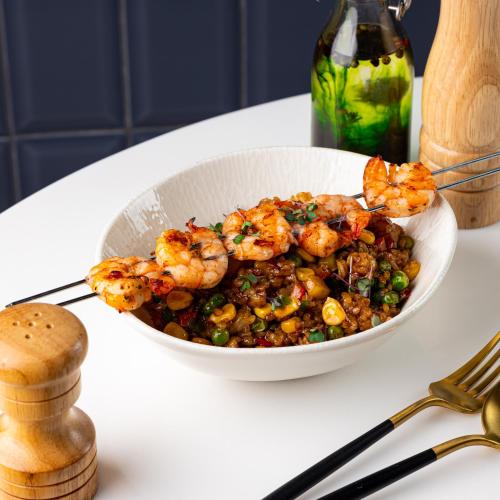 a bowl of food with shrimp and peas on a table at Hotel Bereket Karaganda in Karagandy