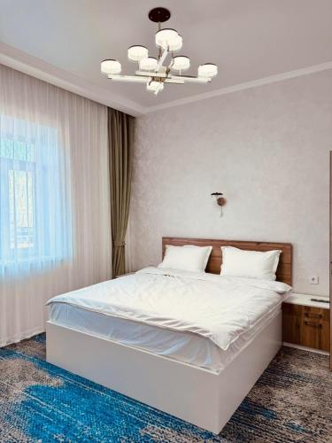 a bedroom with a large white bed with a chandelier at Hotel Bereket Karaganda in Karagandy