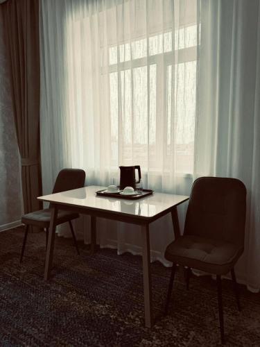 a table and two chairs in front of a window at Hotel Bereket Karaganda in Karagandy