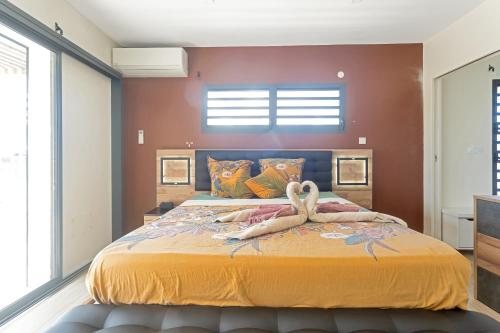 a bedroom with a large bed with two swans on it at Les Villas Jasmin Standing Piscine Chauffée Jacuzzi 5 Ch 14 Pers in Baie-Mahault