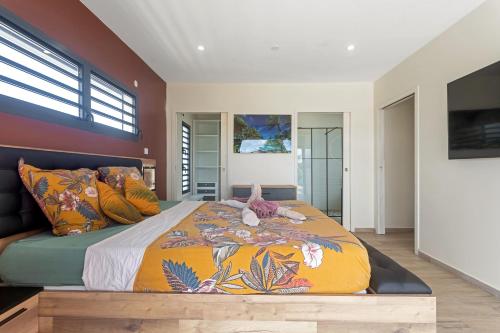 a bedroom with a large bed with colorful pillows at Les Villas Jasmin Standing Piscine Chauffée Jacuzzi 5 Ch 14 Pers in Baie-Mahault