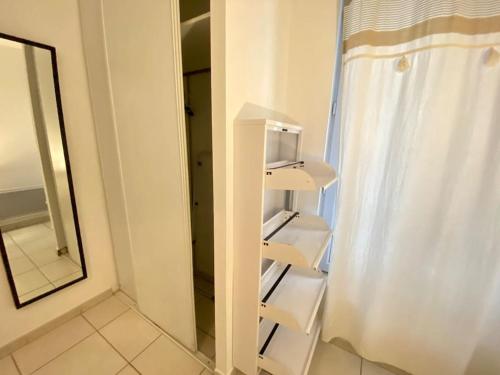 - une étagère blanche dans une salle de bains à côté d'un miroir dans l'établissement Charmant T1 au Cœur de Nimes, à Nîmes