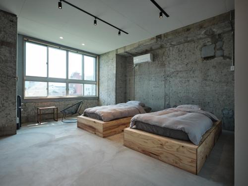 two beds in a room with concrete walls and windows at 三笠館Mikasakan 別館 in Kinokawa