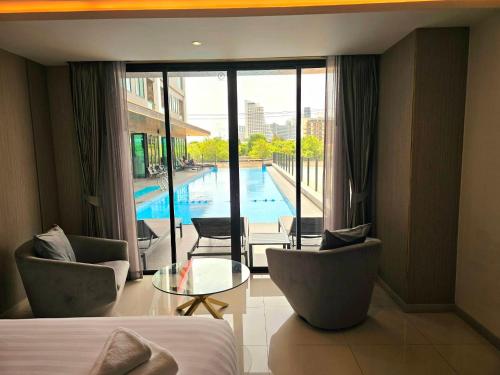 a hotel room with a bed and chairs and a pool at THE TJ HOTEL Pattaya in Jomtien Beach