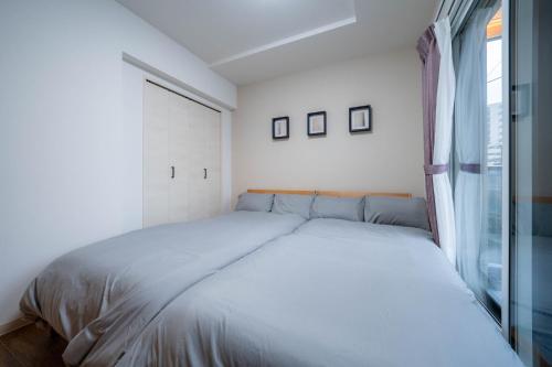a white bedroom with a bed and a window at Zabo Hills 305 in Sapporo