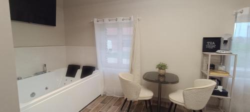 a bathroom with a tub and a table and chairs at Âme O des Flandres La Romantique in Boeschèpe