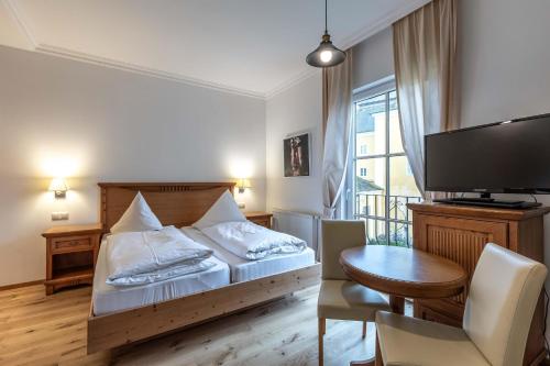 a bedroom with a bed and a desk and a tv at Apartments am Schloss Mühldorf in Feldkirchen an der Donau
