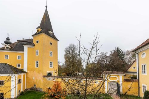 a yellow building with a clock tower in a city at Apartments am Schloss Mühldorf in Feldkirchen an der Donau