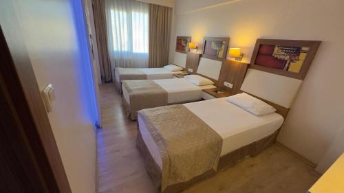 a hotel room with three beds in a room at Hotel Baylan İzmir in Izmir