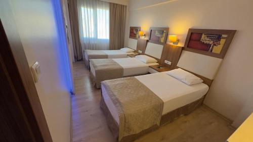 a hotel room with three beds in a room at Hotel Baylan İzmir in Izmir