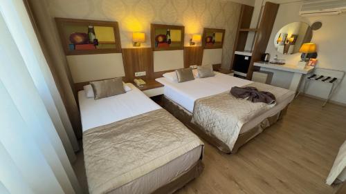a hotel room with two beds and a mirror at Hotel Baylan İzmir in Izmir