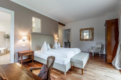 a bedroom with a large white bed and a table at Apartments am Schloss Mühldorf in Feldkirchen an der Donau