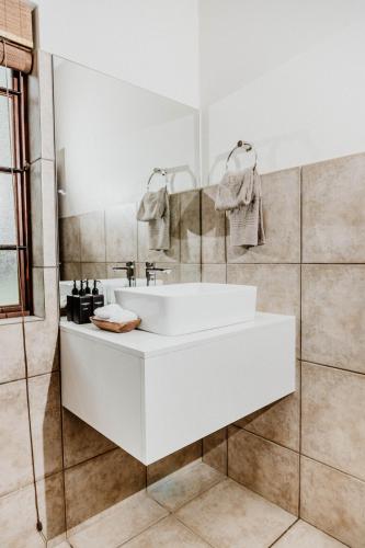 a white bathroom with a sink and a mirror at Filmerton Country Lodge in Kyalami