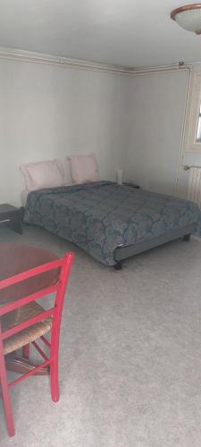 une chambre avec un lit et une chaise rouge dans l'établissement Beau studio, à Châteauroux