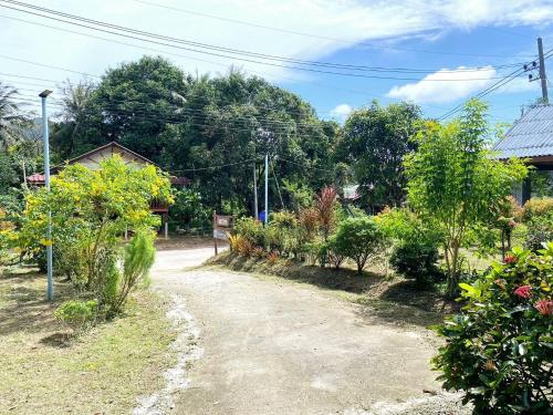 a dirt road in a garden with trees at TR Bungalow in Ban Tha Rua