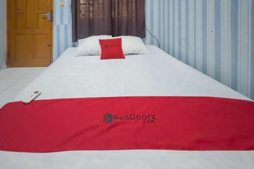 a bed with a red blanket on top of it at RedDoorz at Kuning GH Jatinangor in Sayang