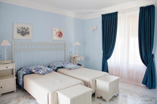 two beds in a bedroom with blue walls and curtains at Hotel Residence Mendolita in Lipari