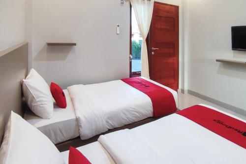 a hotel room with two beds and a television at RedDoorz Syariah at Djaya Guest House Padang in Padang