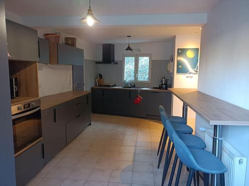 - une cuisine avec des chaises bleues et un comptoir dans une pièce dans l'établissement maison face au château, à Chaumont-sur-Loire