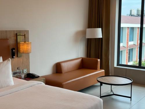 a hotel room with a bed and a chair and a window at Elements by Rosetta- Varca, Goa in Varca