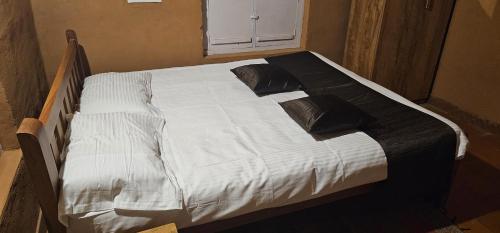 a large white bed with black pillows on it at Kudil Mud Cottages, Cheemeni in Peringom