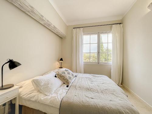une chambre blanche avec un lit et une fenêtre dans l'établissement Villa Miradou - pool, sea and valley view, renovated villa, à Saint-Paul-de-Vence