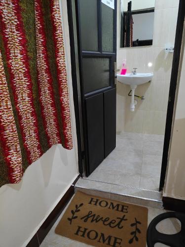 a sign that says home sweet home in front of a bathroom door at Hostel Kiliwood in Moshi