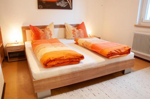 two beds with orange pillows on top of them in a bedroom at Appartement Alberta in Flirsch