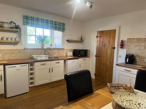 a kitchen with white cabinets and a counter top at Parr Cottage at Snape Castle Mews in Bedale