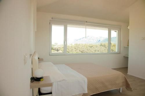 ein weißes Schlafzimmer mit einem Bett und einem Fenster in der Unterkunft Villa Mariarosaria - Dimora Esclusiva con Piscina in Amorosi