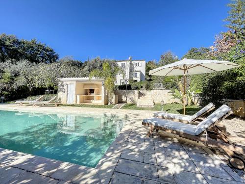 - une piscine avec 2 chaises longues et un parasol dans l'établissement Charming villa with pool, ideal family holiday, à Saint-Paul-de-Vence