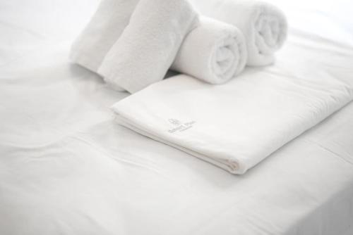 a white towel and two rolls of towels on a bed at Villa Redi Relaxing Spa in Piraeus