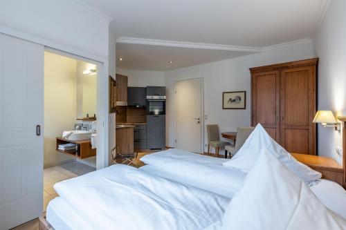 a bedroom with a large white bed and a kitchen at Apartments am Schloss Mühldorf in Feldkirchen an der Donau